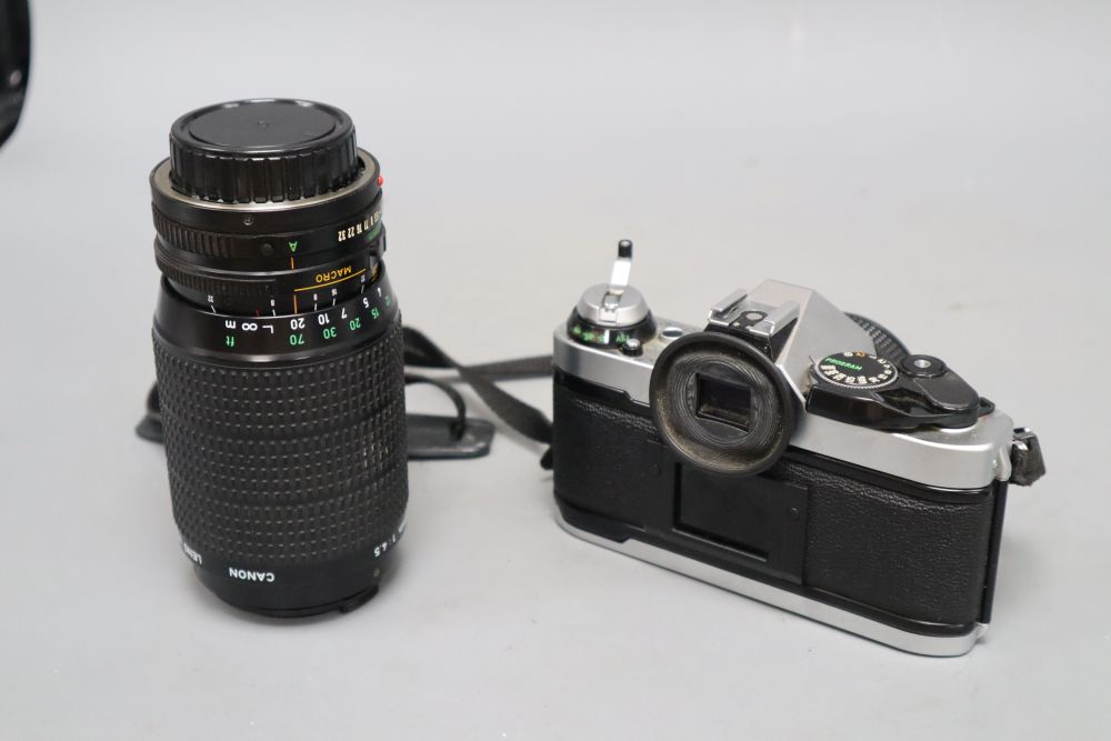 A cased Canon AE-1 programme camera with a 50mm lens, together with a 75-200mm zoom lens, also Canon accessories